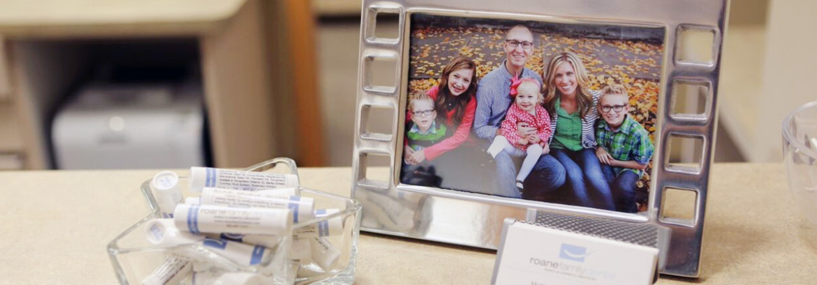 Dr. Roane's family picture with some goodies at the desk Roane Family Dental's office.