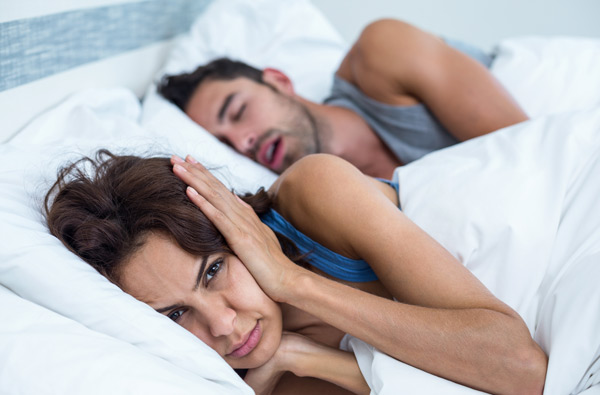 Woman covering ears as husband with sleep apnea snores at Roane Family Dental in West Linn, OR