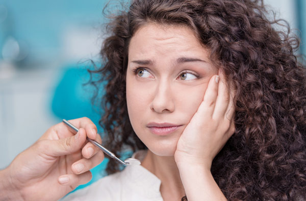 Woman holding cheek due to tooth ache in West Linn, OR.